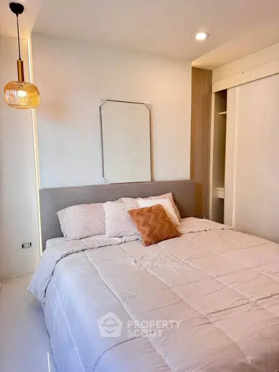 Modern bedroom with cozy bedding and stylish lighting in a contemporary apartment.