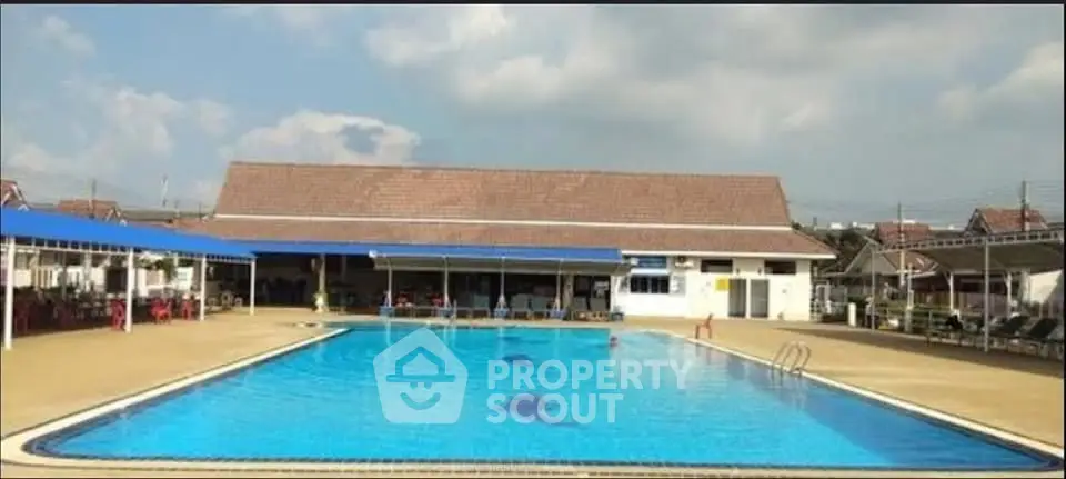 Spacious outdoor swimming pool with clear blue water and surrounding seating area.