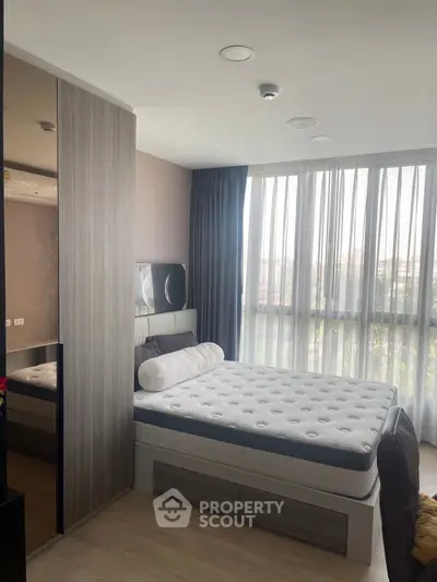 Modern bedroom with large window and stylish decor, featuring a comfortable bed and sleek wardrobe.