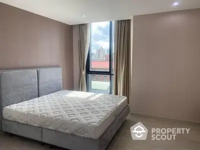 Spacious bedroom with large windows offering ample natural light and a serene city view, featuring a modern king-sized bed.