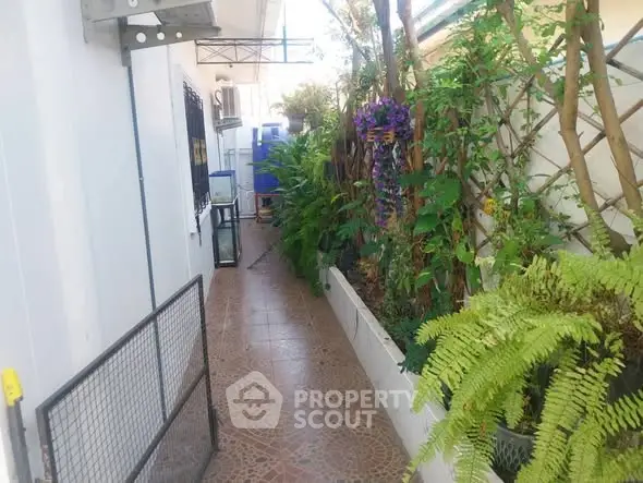 Charming garden pathway with lush greenery and tiled flooring in residential property.