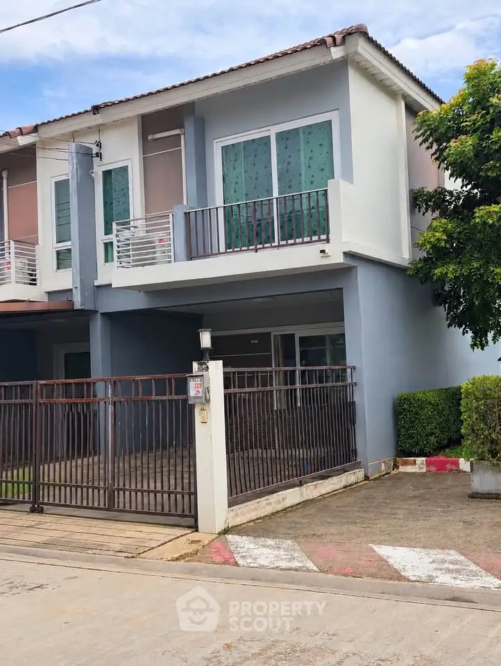 Charming two-story townhouse with balcony and gated driveway in a serene neighborhood.