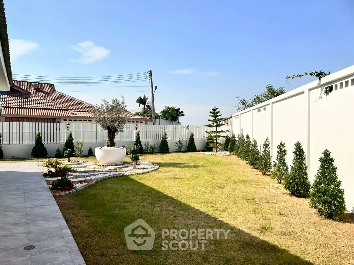 Spacious garden with manicured lawn and decorative plants in a serene residential area.