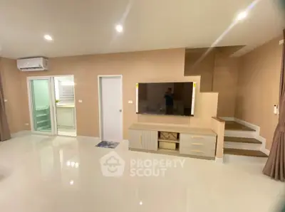 Modern living room with sleek design and built-in storage, featuring a staircase and air conditioning.