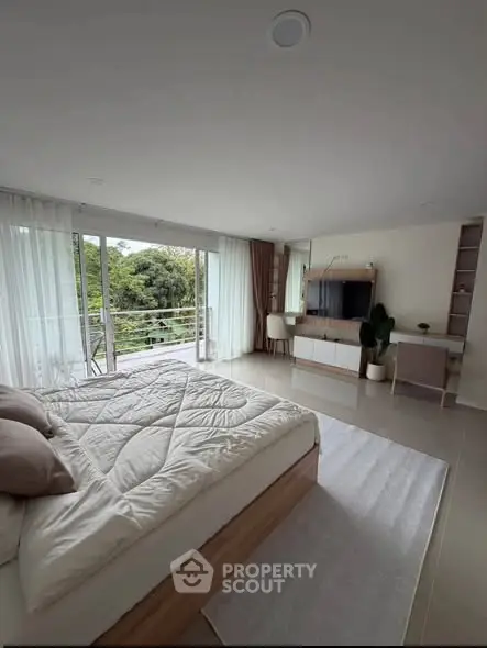 Spacious bedroom with large windows and balcony access, offering serene views and modern decor.