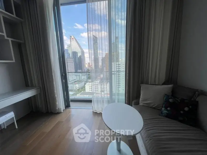 Modern living room with city view, featuring sleek furniture and floor-to-ceiling windows.