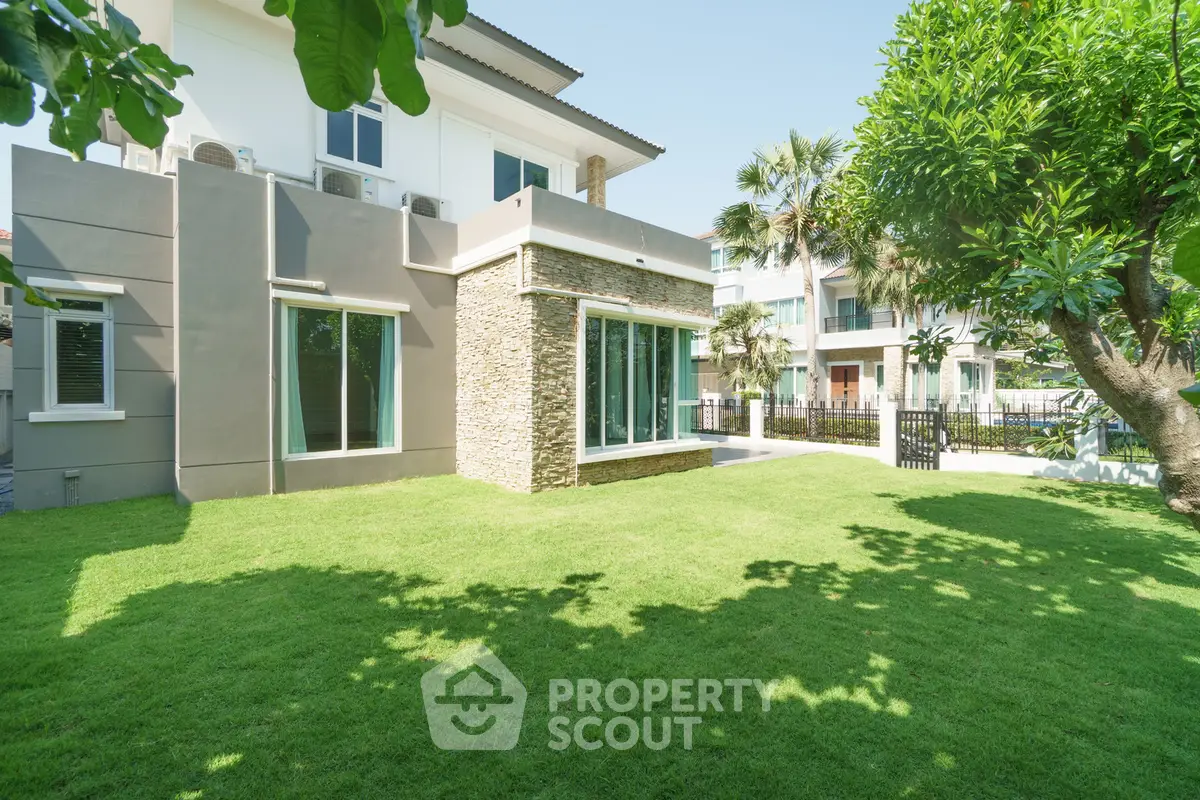 Luxurious modern home with spacious green lawn and elegant exterior design.