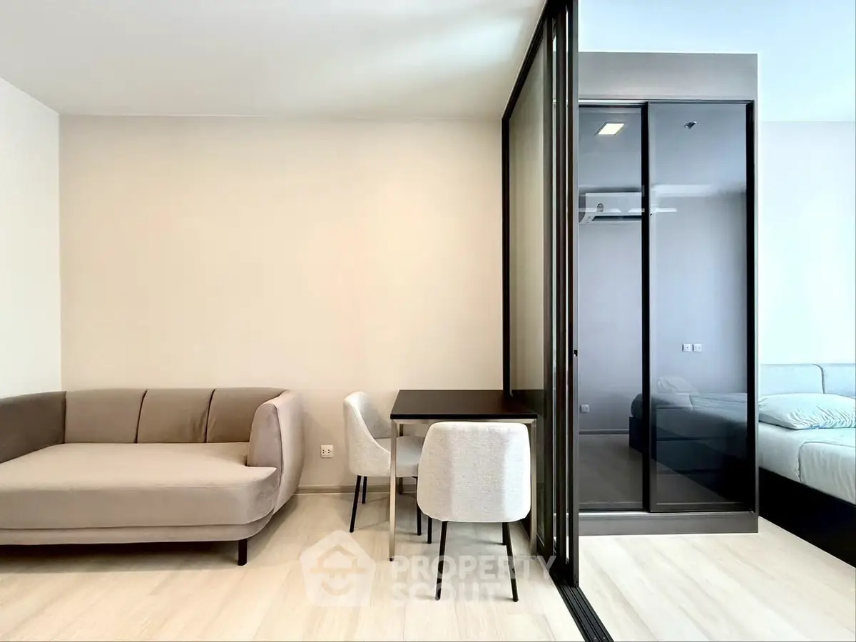 Modern living room with sleek furniture and glass partition to bedroom