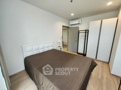 Modern bedroom with sleek design, featuring a comfortable bed, wardrobe, and air conditioning unit.