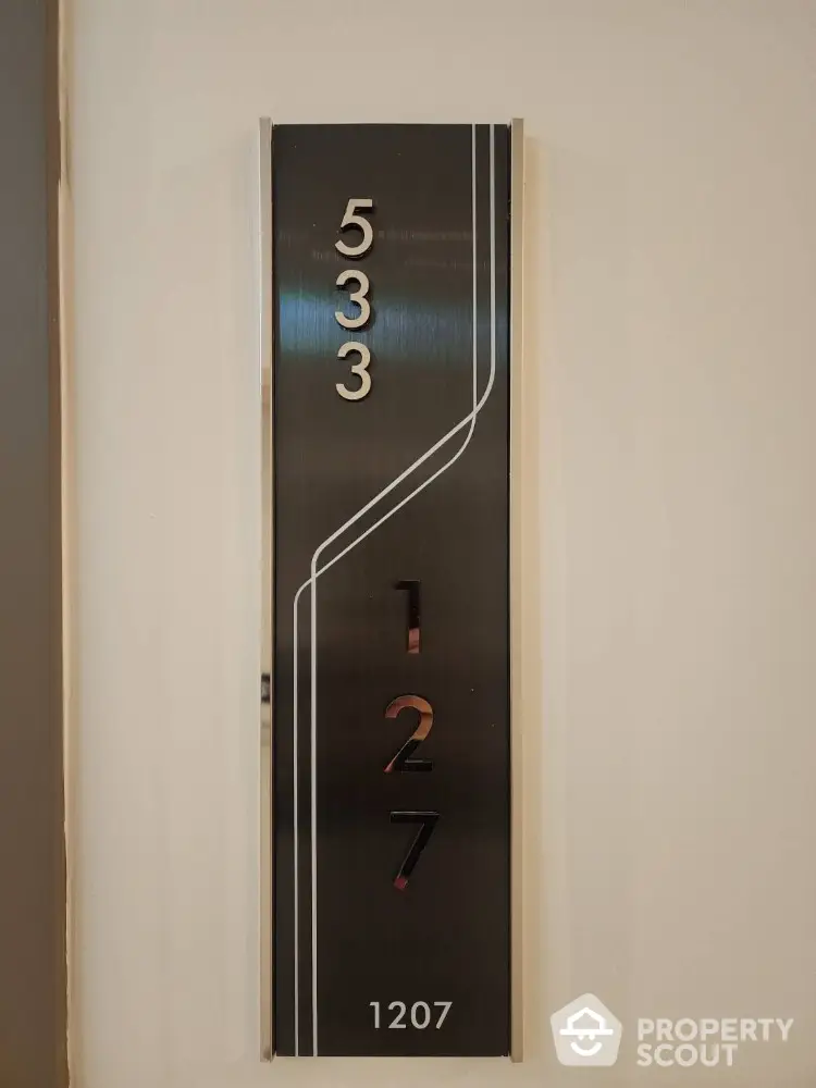 Modern apartment number plaque with sleek design and metallic finish