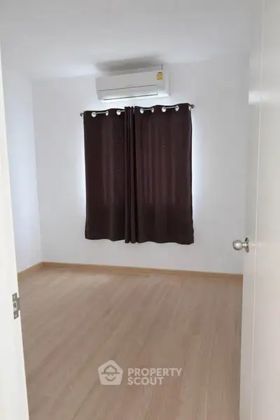 Spacious empty room with wooden flooring and air conditioning, ready for customization.