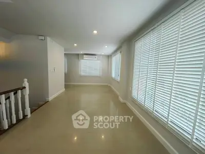 Spacious living room with large windows and modern blinds, perfect for natural light and comfort.