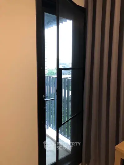 Modern apartment balcony with sleek glass door and city view.