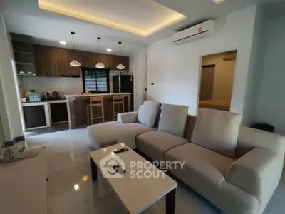 Modern living room with open kitchen, cozy sofa, and stylish lighting in a contemporary apartment.