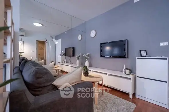 Modern living room with sleek design, featuring a cozy gray sofa, stylish decor, and wall-mounted TV.