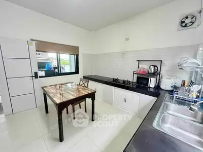 Modern kitchen with sleek countertops, gas stove, and dining area in a bright, spacious layout.