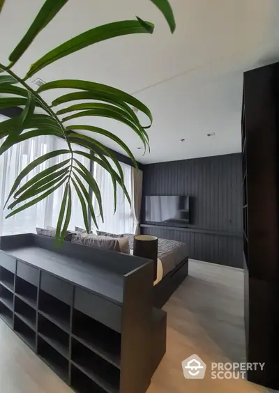 Modern bedroom with sleek black furniture and large window for natural light.