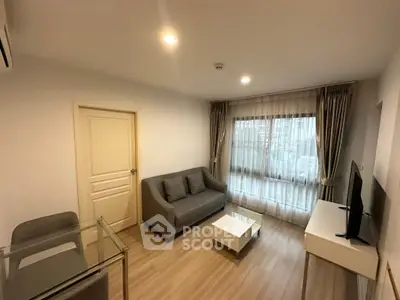 Modern living room with cozy sofa, glass table, and large window with curtains.