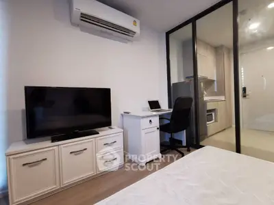 Modern bedroom with TV, desk, and glass partitioned kitchen area