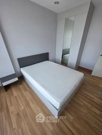 Modern bedroom with minimalist design featuring a sleek bed and mirrored wardrobe.