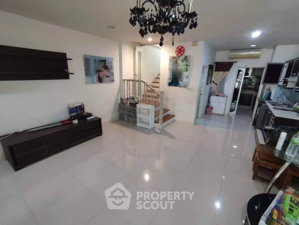 Spacious open-plan living area with modern kitchen and elegant chandelier, perfect for family gatherings.
