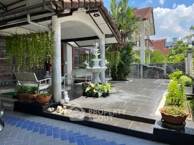Charming house exterior with lush garden and elegant patio, perfect for outdoor relaxation.