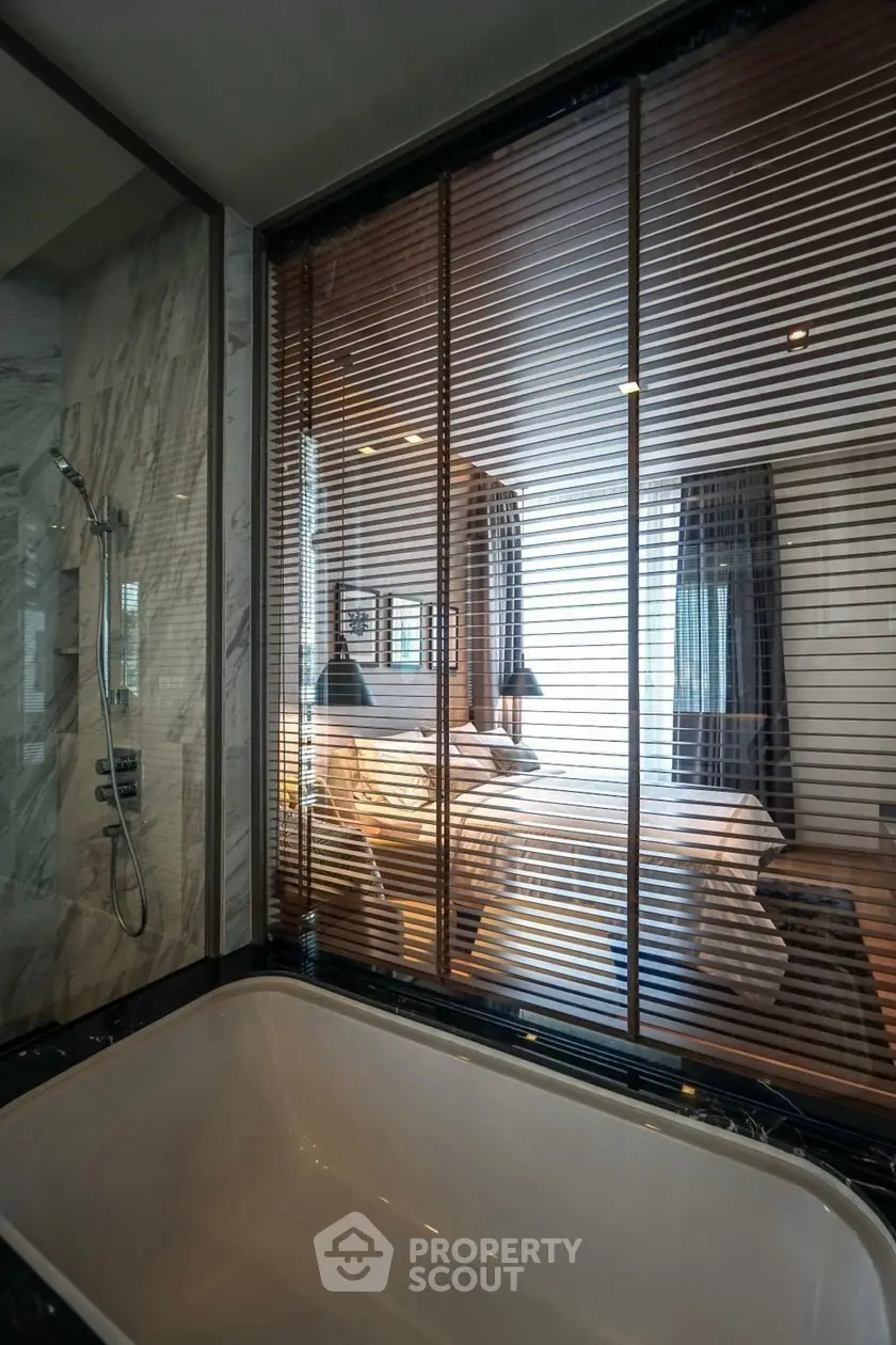 Luxurious bathroom with glass partition overlooking elegant bedroom