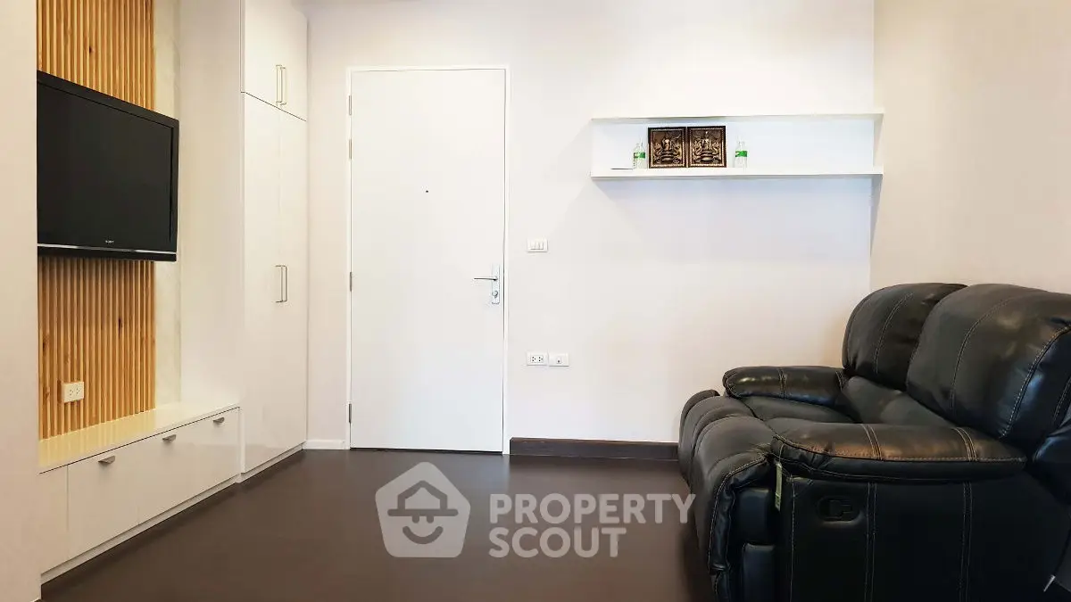 Modern living room with sleek leather sofa and wall-mounted TV, perfect for relaxation.