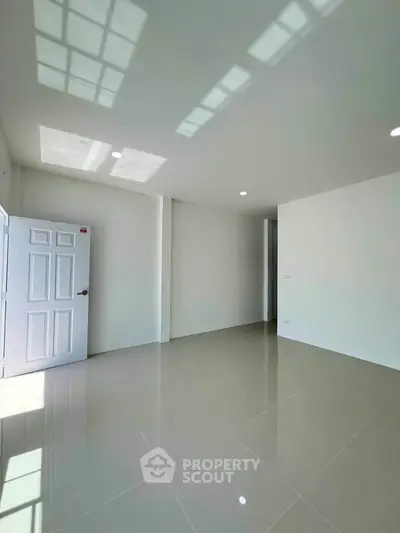Spacious empty room with glossy tiled floor and open door, perfect for customization.