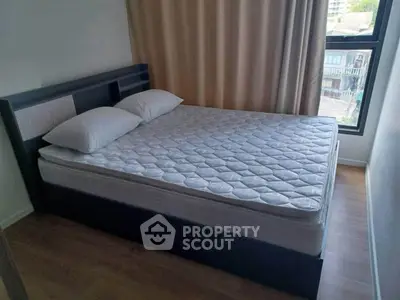 Cozy bedroom with large window and modern bed frame, offering natural light and urban views.