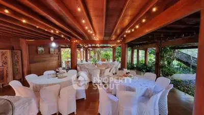 Charming rustic event space with wooden beams and garden view, perfect for gatherings.