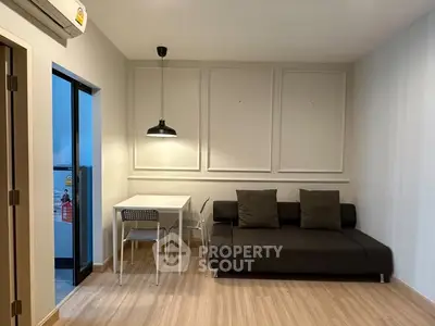Modern living room with sleek sofa and dining area, featuring minimalist decor and warm lighting.