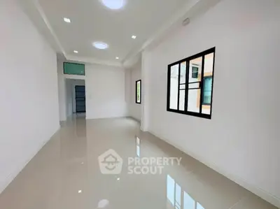 Spacious and bright empty room with glossy tiled floors and large windows.