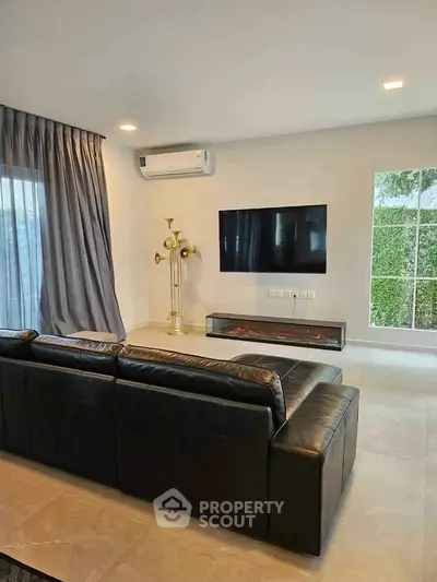 Modern living room with sleek black sofa, wall-mounted TV, and elegant floor lamp.