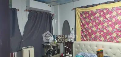 Cozy bedroom with eclectic decor and air conditioning unit, featuring a tufted headboard and colorful curtains.