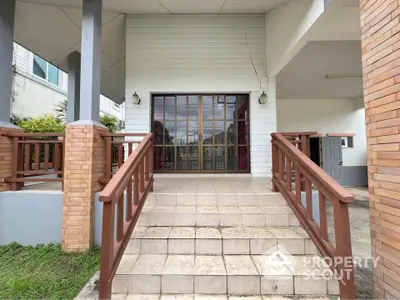 Charming entrance with wooden railings and tiled steps leading to a cozy home.