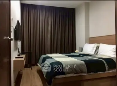 Cozy bedroom with modern decor and large window with dark curtains.