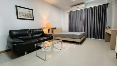 Modern studio apartment with sleek black leather sofa and minimalist decor