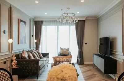 Elegant living room with modern decor and large windows, featuring a stylish chandelier and comfortable seating.