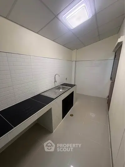 Modern kitchen with sleek black countertops and white tile backsplash