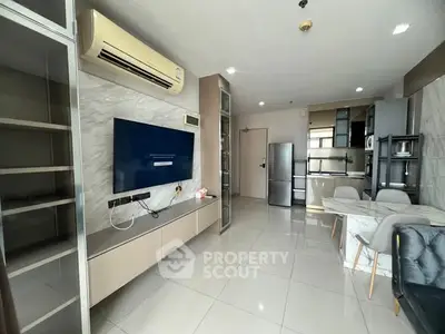 Modern living room with sleek design, featuring a wall-mounted TV, air conditioning, and open kitchen layout.
