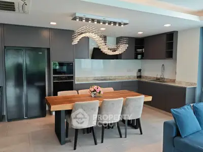 Modern kitchen with sleek cabinetry, elegant dining area, and stylish lighting fixture.