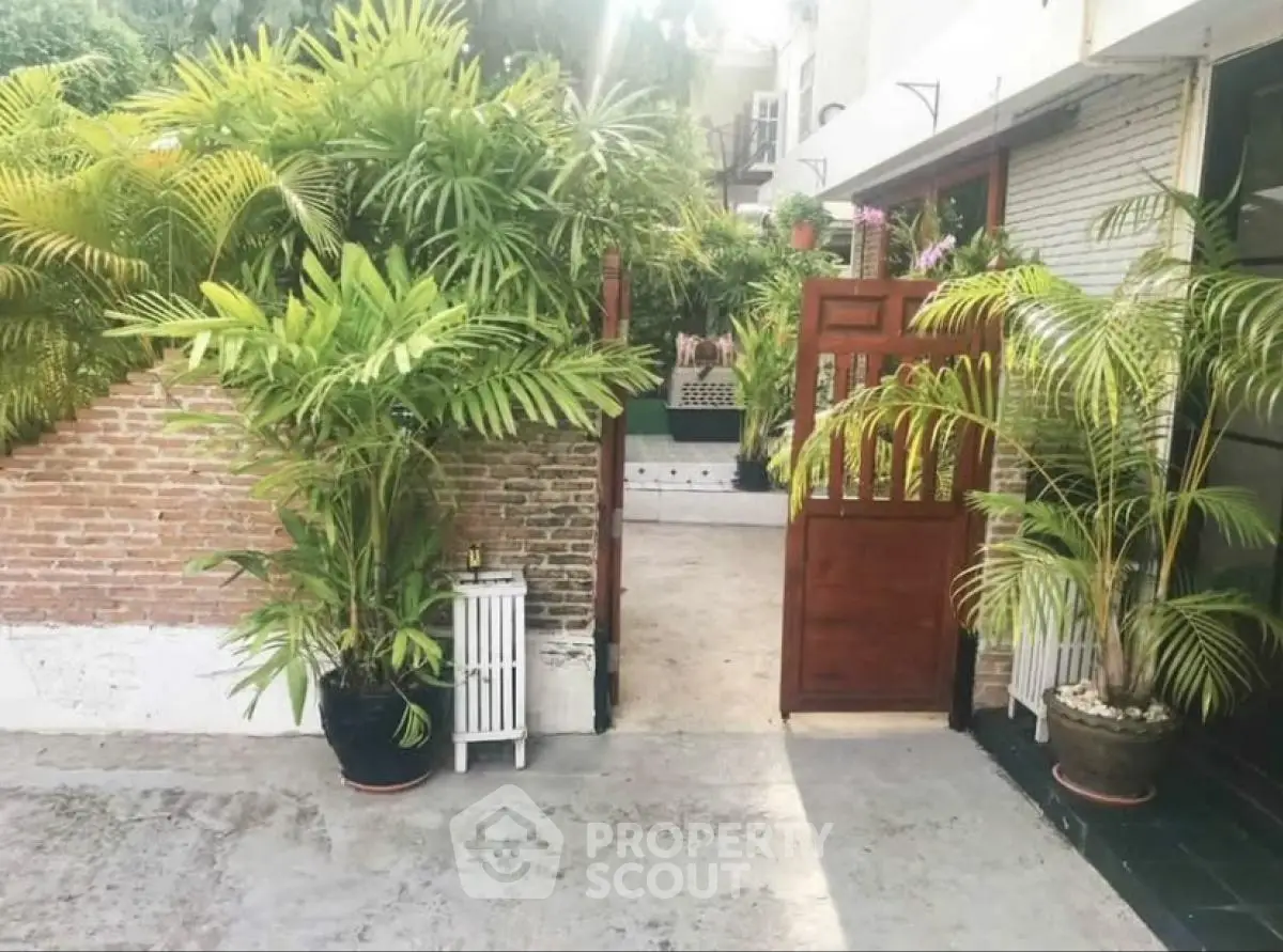 Charming garden entrance with lush greenery and brick wall, perfect for a serene home ambiance.