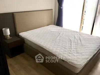 Cozy bedroom with modern bed and natural light from large window.
