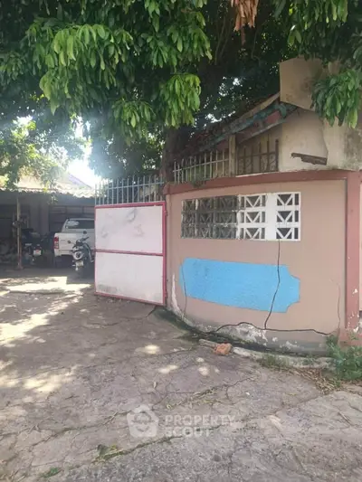 Charming rustic entrance with open gate and lush greenery, perfect for a cozy home setting.