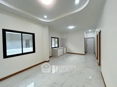 Spacious modern interior with elegant ceiling design and large windows.