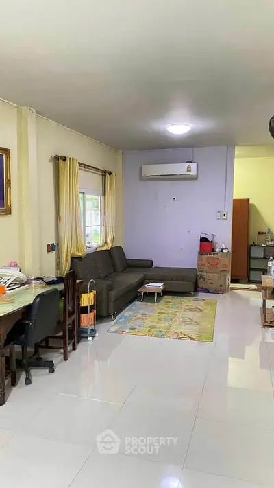 Spacious living room with modern sofa and air conditioning, perfect for family gatherings.