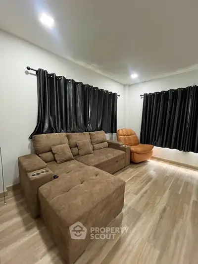 Spacious living room with modern brown sofa and sleek black curtains, perfect for relaxation.