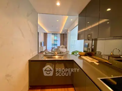 Modern kitchen with sleek design and open layout leading to a stylish living room.