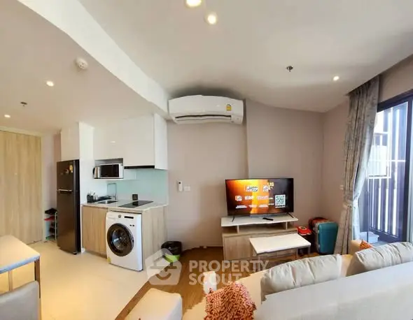 Modern living room with open kitchen, featuring washing machine and TV setup, ideal for urban living.